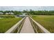 Inviting long wooden dock stretching across marshland leading to a boat and covered dock area, with lush greenery at 2834 Parkers Landing Rd, Mount Pleasant, SC 29466
