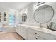 Bright bathroom featuring double sinks, modern fixtures, round mirrors, and a soaking tub at 4272 Persimmon Woods Dr, Charleston, SC 29420