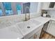 Up close shot of a white farmhouse sink, with white backsplash, marble countertops, and updated faucet at 4272 Persimmon Woods Dr, Charleston, SC 29420