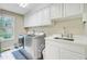Well-equipped laundry room featuring white cabinets, sink, and stainless steel washer and dryer at 4272 Persimmon Woods Dr, Charleston, SC 29420