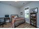 Bedroom with a metal frame bed, wood floors, light-grey walls, one window, and a wooden bookcase filled with memorabilia at 436 Ripple Park Dr, Summerville, SC 29486