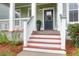 Welcoming front door entrance with red painted steps, white railing, and greenery at 5242 E Dolphin St, North Charleston, SC 29405