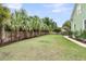 Spacious backyard with palm trees, a green lawn, brick border, and wood fence providing privacy at 591 Two Mile, Johns Island, SC 29455