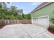 Large two car garage with white doors, green siding, and additional paved parking with a wooden fence at 591 Two Mile, Johns Island, SC 29455