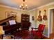 Music room with a piano, vintage red chair, and hardwood flooring at 8 Brisbane Dr, Charleston, SC 29407