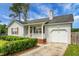 Attractive single-story home featuring a cozy front porch, garage, trimmed hedge and lovely landscaping at 8692 Bentwood Dr, North Charleston, SC 29406
