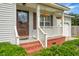 Close-up of a front porch with brick foundation, decorative door wreath and hanging plants, adding charm and curb appeal at 8692 Bentwood Dr, North Charleston, SC 29406
