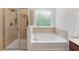 This bathroom features a tiled shower, a soaking tub, and a large window letting in natural light at 9713 Cutleaf Dr, Ladson, SC 29456