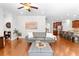 Bright living space with hardwood floors, gray sofa, and an open floor plan leading to the kitchen at 9713 Cutleaf Dr, Ladson, SC 29456