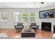 Open living room with natural light, hardwood floors, fireplace, and gray modern furniture at 9713 Cutleaf Dr, Ladson, SC 29456