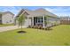 Attractive home exterior featuring a manicured lawn, young tree, and covered porch with white columns at 104 Wild Orchid Way, Huger, SC 29450