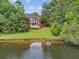 A serene view of the home's exterior overlooking the water with lush greenery and a charming patio area at 115 Old Postern Rd, Summerville, SC 29483