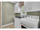 Functional laundry room with tile flooring, white cabinets, sink, and modern washer and dryer at 115 Old Postern Rd, Summerville, SC 29483