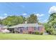 Charming brick home with green lawn, dark shutters, and mature trees under a sunny blue sky at 1237 Fort Dr, Hanahan, SC 29410