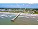 Beachfront condos with a pier and a bustling beach with blue umbrellas and clear waves at 1400 Ocean Blvd # 106B, Isle of Palms, SC 29451