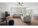 Spacious living room with an L-shaped sofa, hardwood floors, and a ceiling fan, seamlessly connected to the dining area at 141 Sweet Cherry Ln, Summerville, SC 29486