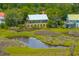 An aerial view of a home nestled among lush greenery near a scenic marsh at 1520 Regimental Ln, Johns Island, SC 29455