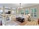 Bright living room features a large sectional sofa, hardwood floors, and plentiful natural light from the windows at 1664 William Hapton Way, Mount Pleasant, SC 29466