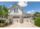 Charming white home featuring a two-car garage with decorative latticework and updated light fixtures, all under a bright blue sky at 371 Bridgetown Pass, Mount Pleasant, SC 29464
