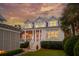 Beautiful home with a welcoming front porch illuminated by warm lights, set against a stunning sunset sky at 371 Bridgetown Pass, Mount Pleasant, SC 29464
