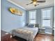 Bedroom with light blue walls, wood floor, ceiling fan, and surfboard decor at 4 Line St, Charleston, SC 29403