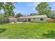 A serene backyard features lush green grass, mature trees, a patio area with a grill, and a charming single-story home at 402 Woodward Blvd, Summerville, SC 29483