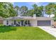 Well-maintained single-story home with a gray front door, garage, and a lush green lawn at 402 Woodward Blvd, Summerville, SC 29483