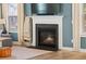 Close-up of a modern fireplace with a white mantel and a cozy fire, flanked by windows and a decorative blanket ladder at 443 Coopers Hawk Dr, Summerville, SC 29483