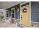 Charming home featuring a welcoming yellow front door with stone accents and a cozy porch with rocking chairs at 443 Coopers Hawk Dr, Summerville, SC 29483