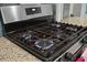 Close-up of a stainless steel gas range with burners ignited, showcasing modern kitchen appliances and granite counter tops at 443 Coopers Hawk Dr, Summerville, SC 29483