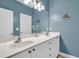 Bathroom with blue walls, double sinks, white cabinetry, and nautical-themed decor at 4630 Palm View Cir, North Charleston, SC 29418