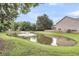 Beautiful pond view surrounded by green grass and lush trees with fountain in the center at 4630 Palm View Cir, North Charleston, SC 29418