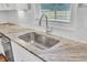 Close-up of a kitchen sink with stone countertop, stainless steel faucet, white backsplash, and a window view at 528 Fern Tree Dr, Summerville, SC 29486
