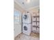 Bright laundry room featuring stacked washer and dryer, storage shelving, and tiled floor near an exterior door at 634 Lynne Ave, Charleston, SC 29412