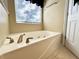 Bathroom showcasing a soaking tub with chrome fixtures and a window at 7277 Sweetgrass Blvd, Hanahan, SC 29410