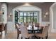Elegant dining room with round wood table and views to the outdoor seating through large windows at 79 Trailing Vine Way, Kiawah Island, SC 29455