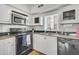 Well-lit kitchen featuring white cabinets, dark countertops and stainless steel appliances at 10 Trapman St, Charleston, SC 29401