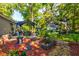 Landscaped backyard featuring a covered patio, green lawn, shed, and vibrant flower beds at 102 Cottonwood Dr, Summerville, SC 29483