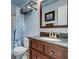Bright bathroom featuring a dark wood vanity, a mirror, a sink, a toilet and a shower with a white curtain at 102 Cottonwood Dr, Summerville, SC 29483
