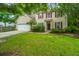 Charming two-story home with beige siding, red shutters, a well-manicured lawn, and an attached two-car garage at 1629 Jorrington Street St, Mount Pleasant, SC 29466