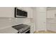 Close-up of a modern kitchen with stainless steel microwave, range, white cabinets, and white subway tile backsplash at 205 Bilge Rd, Ridgeville, SC 29472