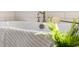 Close up of white soaking tub with bronze fixtures, tile surround, and decorative plant at 2356 Hut Creek Rd, Johns Island, SC 29455