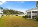 Spacious backyard with green grass, screened-in porch, and young trees under a bright, sunny sky at 347 Ripple Park Dr, Summerville, SC 29486