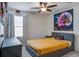 Bedroom with a ceiling fan, window, and artistic wall decor above gray bed with orange comforter at 357 Beachgrass Ln, Summerville, SC 29486