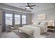 A staged main bedroom featuring a ceiling fan, seating, three windows with views and neutral decor at 357 Beachgrass Ln, Summerville, SC 29486