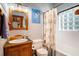 Well-lit bathroom features a wood vanity, glass block window, and shower with a patterned curtain at 520 E Huron Ave, Folly Beach, SC 29439