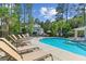 Community pool featuring plenty of lounge seating and a nearby pool house surrounded by lush trees at 542 Amalie Farms Dr, Charleston, SC 29492