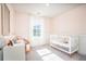 Bright bedroom with pink walls featuring a white crib, chair and white desk at 551 Blue Mistflower Dr, Moncks Corner, SC 29461