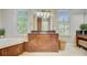 Elegant bathroom with a granite countertop, custom wood cabinetry, a soaking tub, and natural light from large windows at 750 Navigators Run, Mount Pleasant, SC 29464