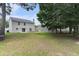 A spacious grassy backyard with a view of the back of the house and mature trees at 8044 Old London Rd, North Charleston, SC 29406